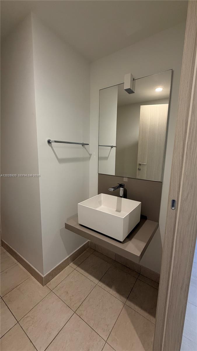 1000 Brickell, Unit 2014 Miami, FL 33131 - Photo 22 of 30 a bathroom with a sink a mirror and shower