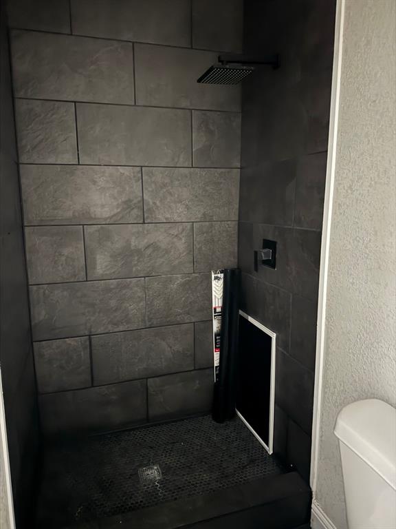 9551 Lechner Road, Unit G Fort Worth, TX 76179 - Photo 13 of 15 Shower stall featuring dark gray rectangular wall tiling, a black square rain shower head, and a black shower control
