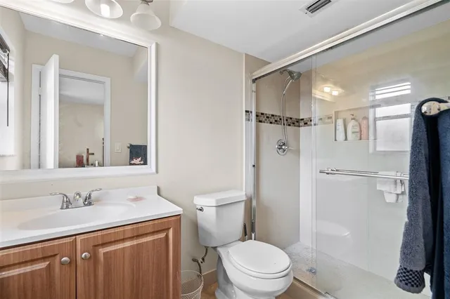 a bathroom with a shower sink vanity mirror and toilet