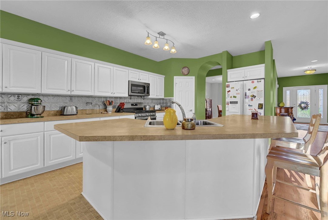 2690 Mayfair Road Akron, OH 44312 - Photo 7 of 31 Kitchen featuring white cabinets, stainless steel appliances, a breakfast bar area, a spacious island, and light countertops