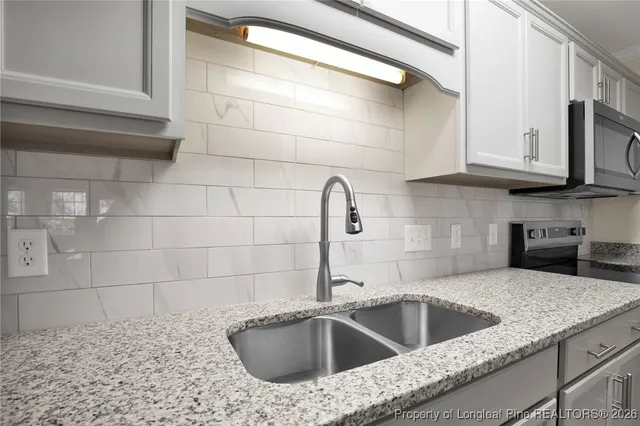 a kitchen with stainless steel appliances granite countertop a refrigerator a stove and a sink with wooden floor