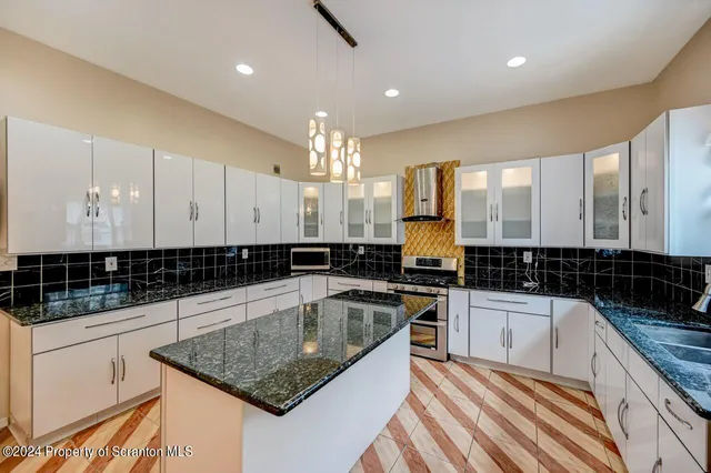 a kitchen with granite countertop a sink a stove and cabinets