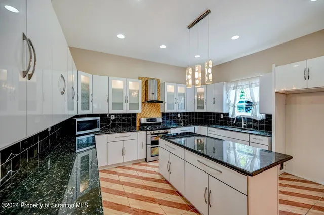 a kitchen with granite countertop a sink cabinets and stainless steel appliances