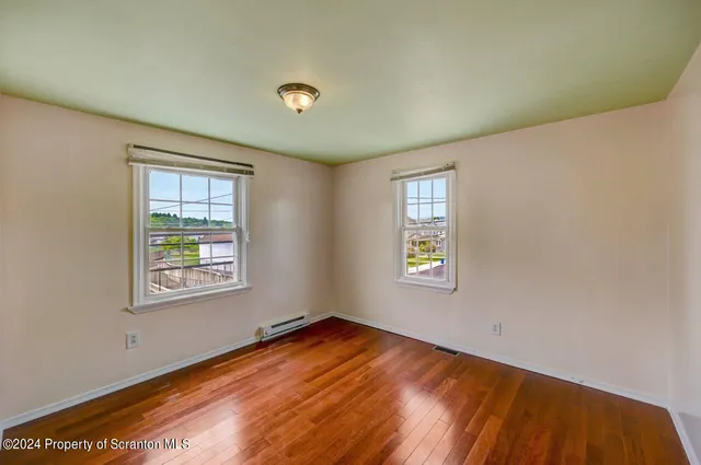 a view of empty room with window and wooden floor