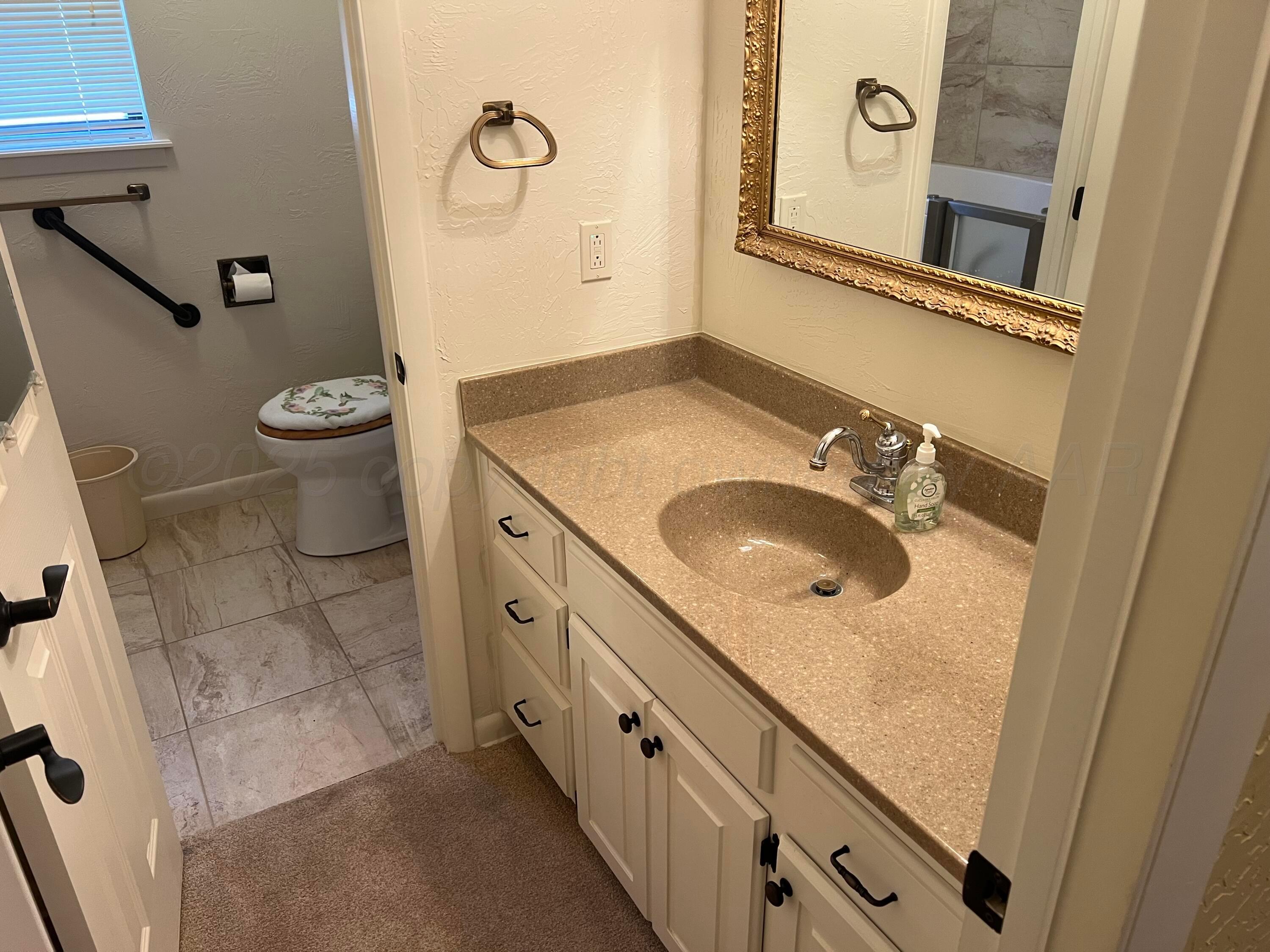 7115 Gainsborough Road Amarillo, TX 79106 - Photo 33 of 81 a bathroom with a granite countertop sink a toilet and a mirror