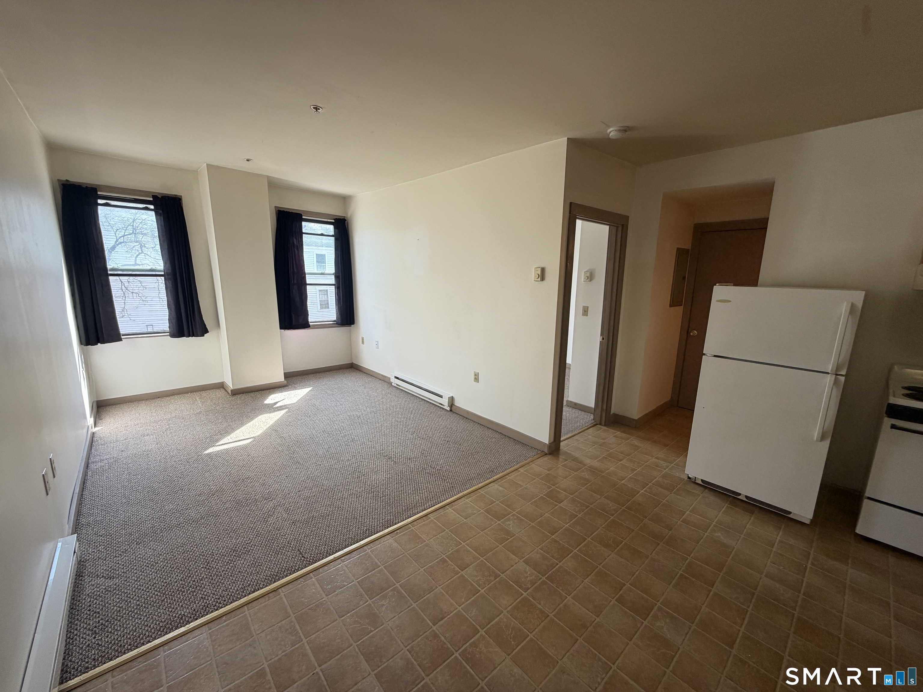 277 North Main Street, Unit 3 Winchester, CT 06098 - Photo 3 of 14 an empty room with windows and refrigerator