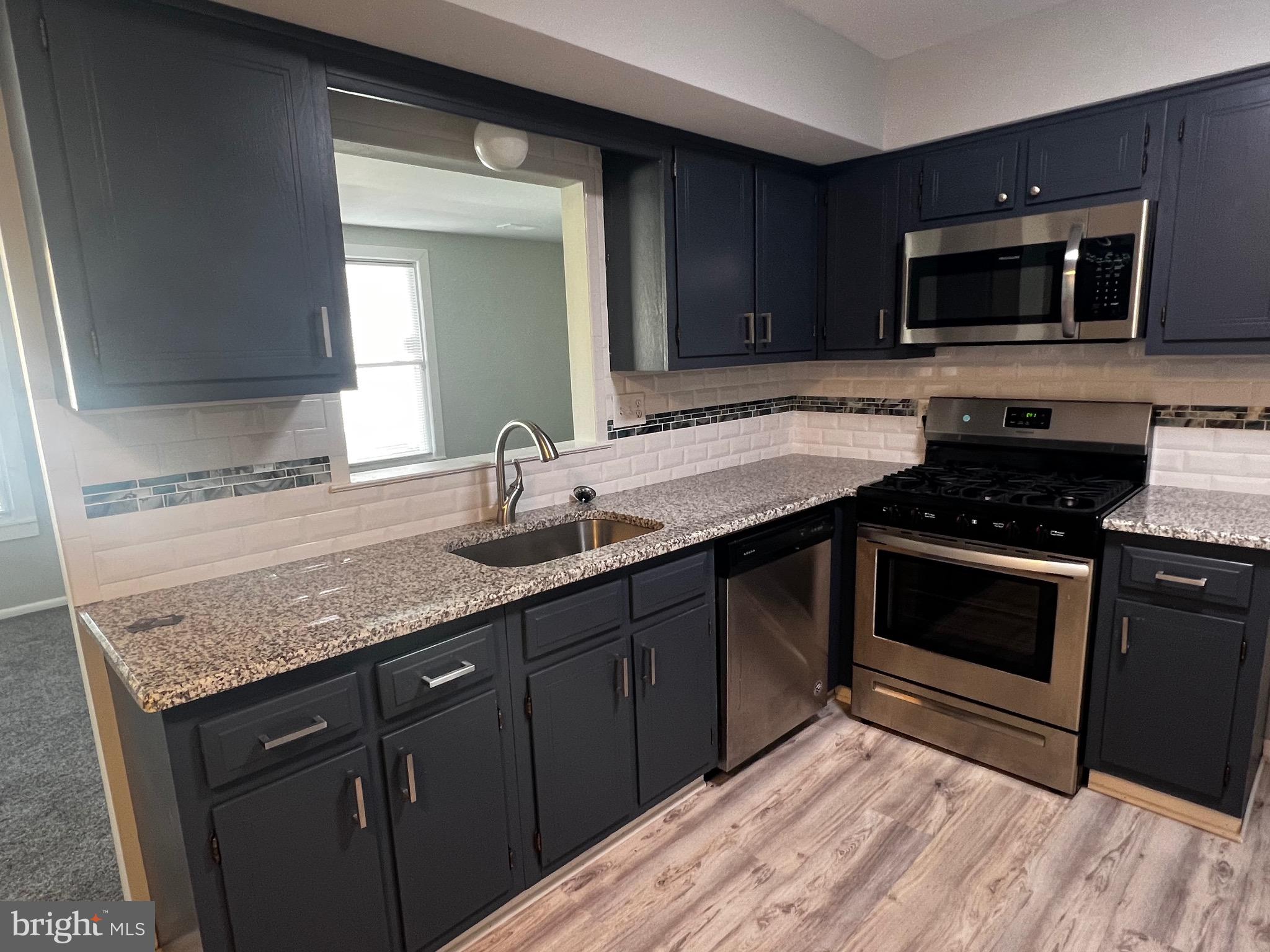 1756 Hybrid Place Clementon, NJ 08021 - Photo 4 of 13 a kitchen with granite countertop a sink and a stove top oven with wooden floor