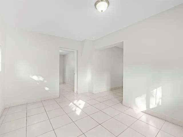 a view of an empty room with window and chandelier fan