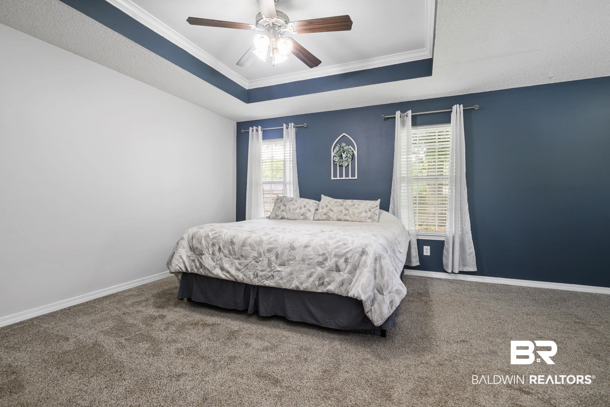 9422 Labrador Run South Mobile, AL 36695 - Photo 17 of 36 Spacious room featuring a tray ceiling with a ceiling fan, plush carpet flooring, and two windows with blinds