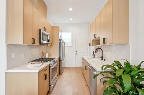 a kitchen with stainless steel appliances a sink a stove top oven a counter space and cabinets