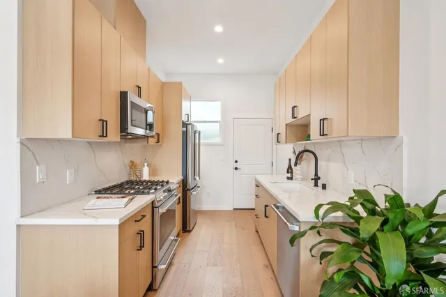 a kitchen with stainless steel appliances a sink a stove top oven a counter space and cabinets