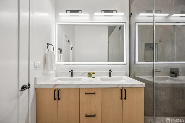 a bathroom with a sink double vanity granite tub shower and a mirror