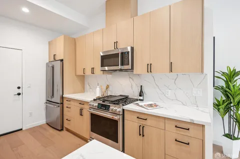 a kitchen with granite countertop a stove a sink and a refrigerator