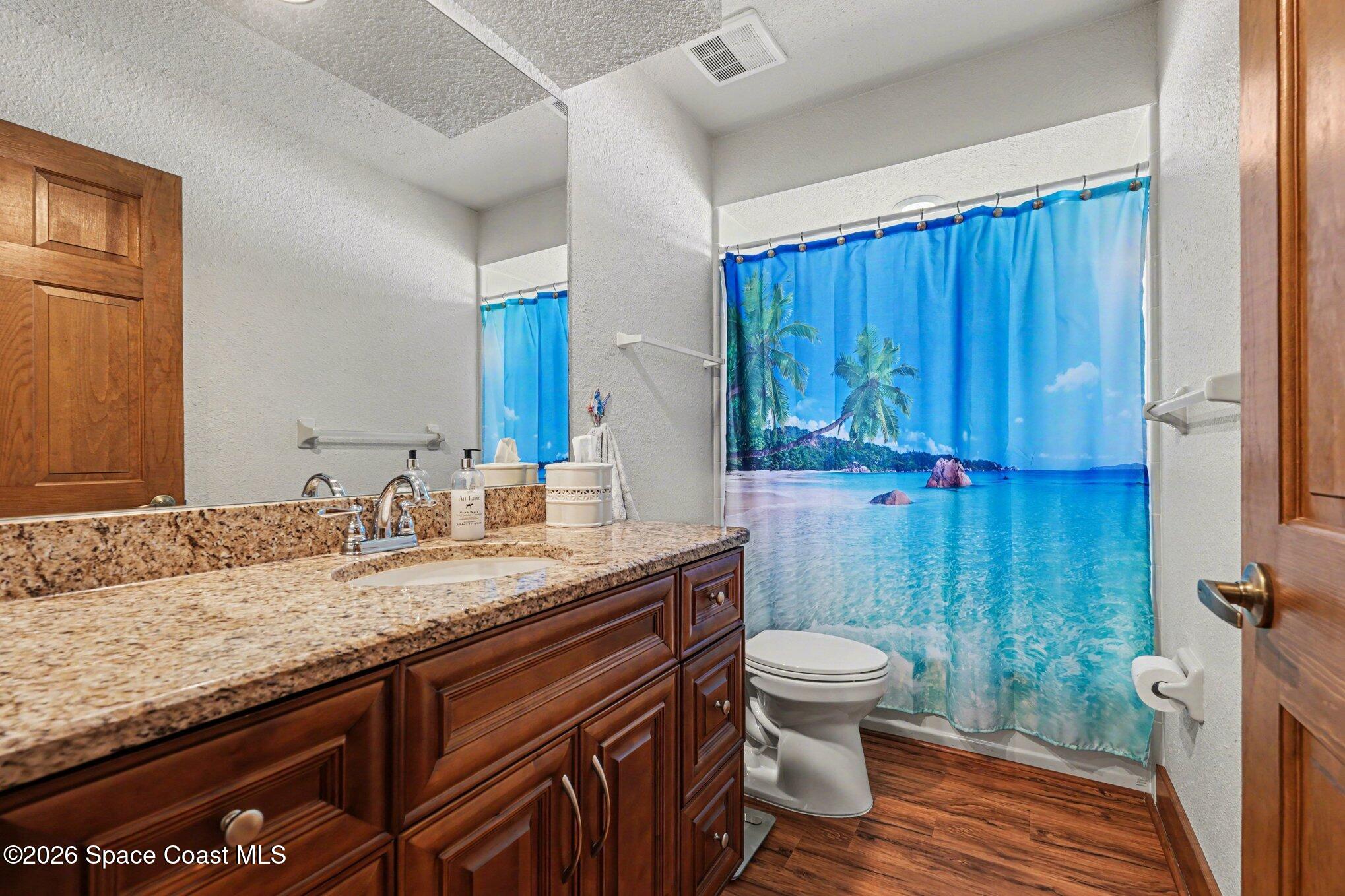 2604 Senator Way Melbourne, FL 32901 - Photo 21 of 27 a bathroom with a granite countertop sink a toilet and a shower