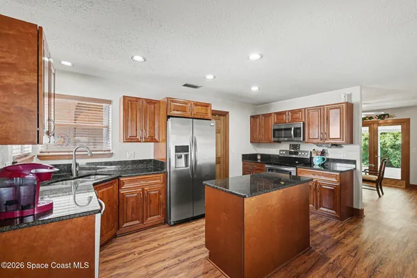 a kitchen with stainless steel appliances granite countertop a refrigerator a sink and a stove