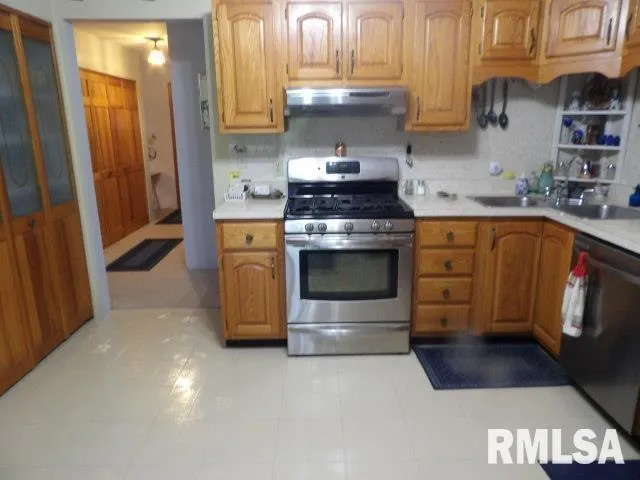 a kitchen with stainless steel appliances a stove a sink dishwasher and cabinets with wooden floor