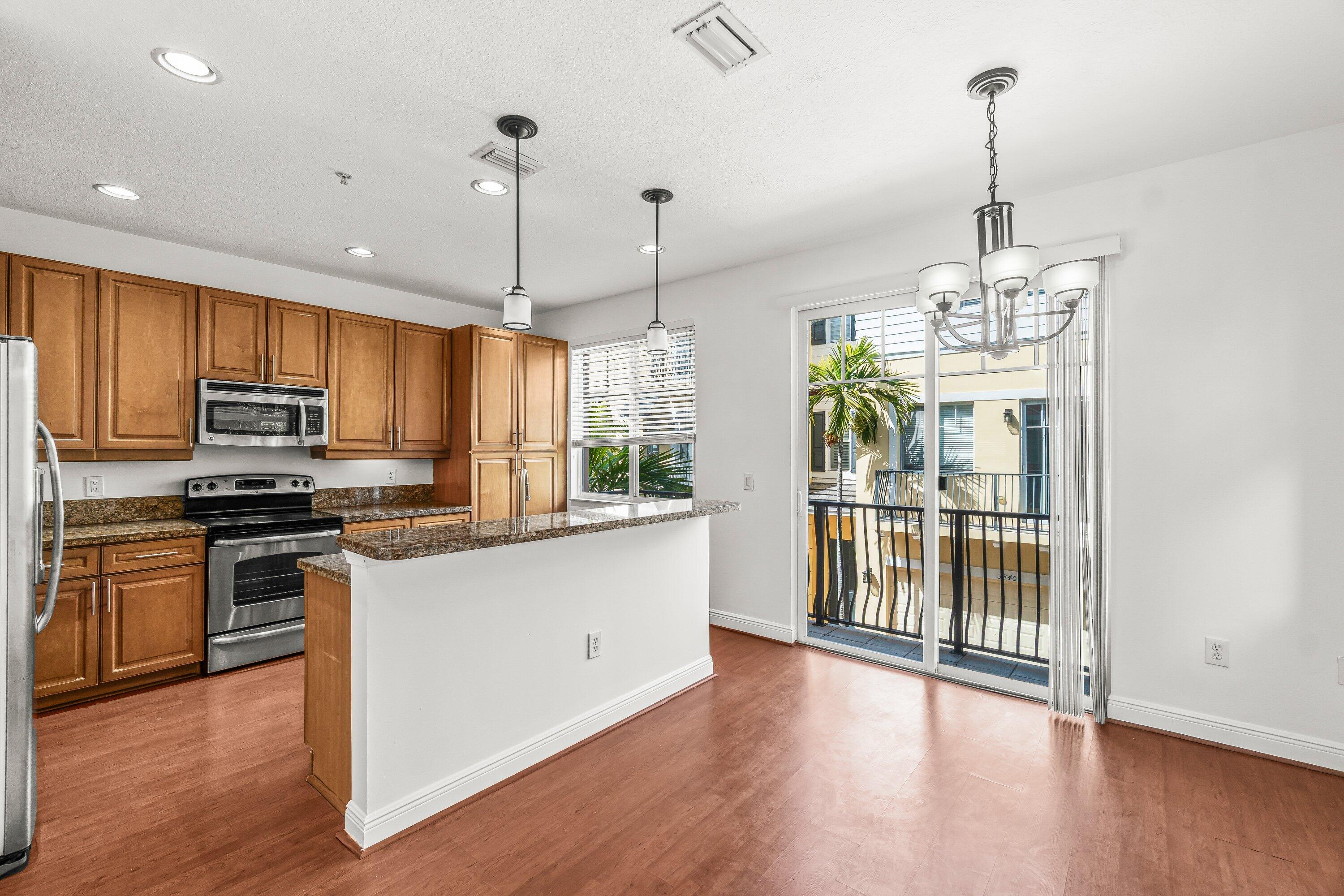 3830 Northwest 5th Terrace Boca Raton, FL 33431 - Photo 14 of 30 a kitchen with stainless steel appliances granite countertop a refrigerator a stove top oven a sink and dishwasher with wooden floor