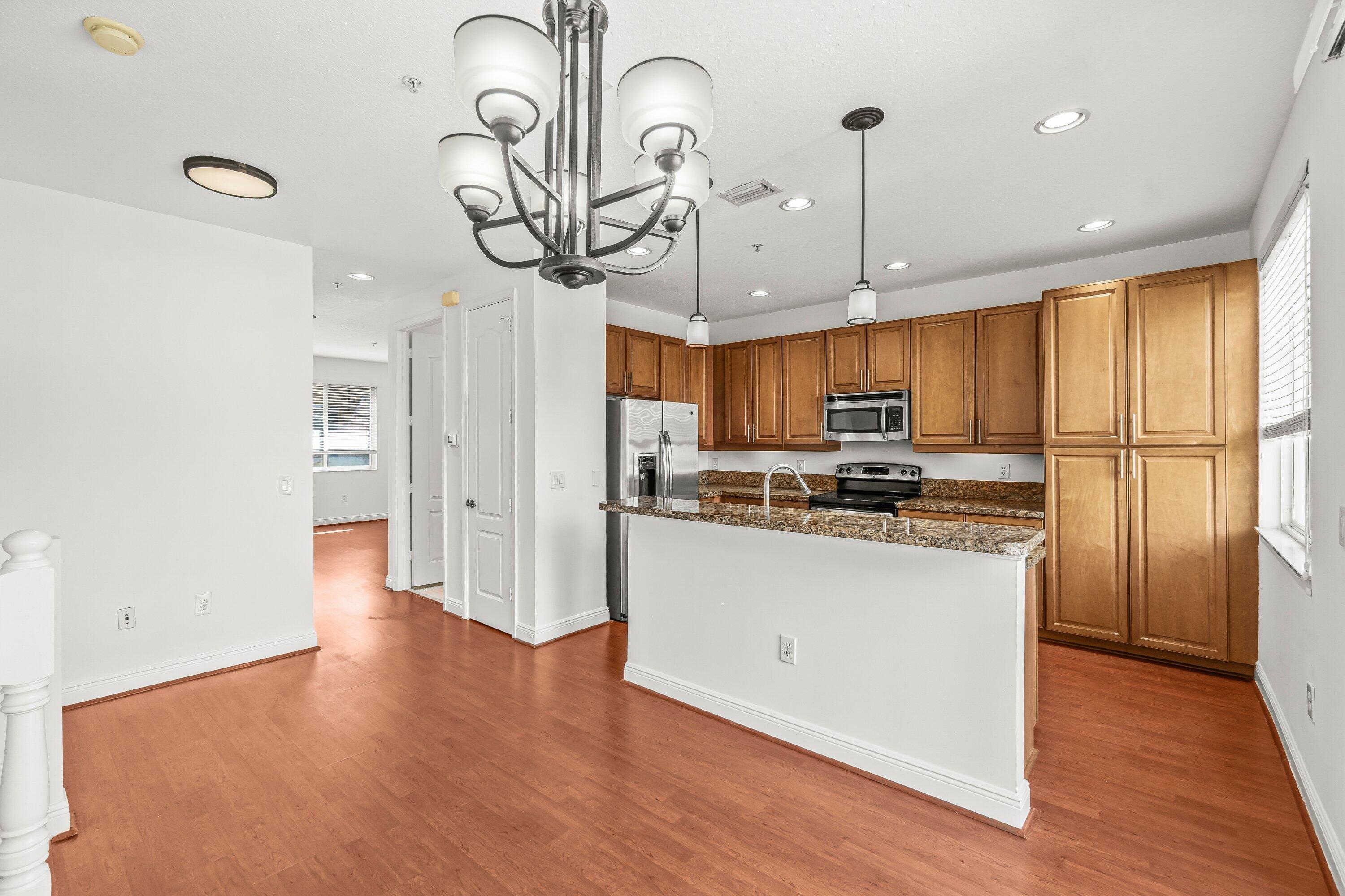 3830 Northwest 5th Terrace Boca Raton, FL 33431 - Photo 9 of 30 a kitchen with stainless steel appliances granite countertop a refrigerator a sink dishwasher a stove and a dining table with wooden floor