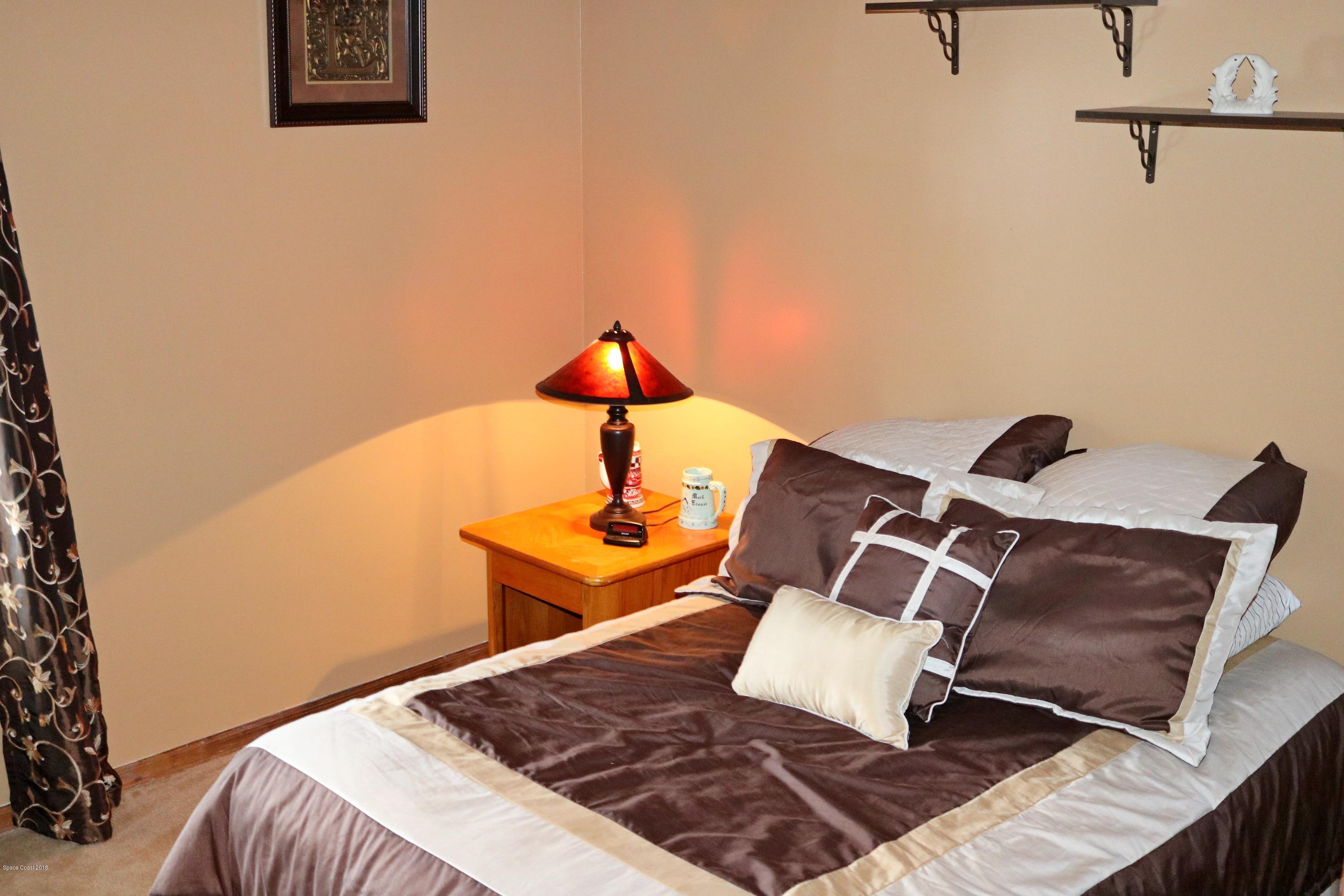 6154 Corning Road Cocoa, FL 32927 - Photo 9 of 16 a bedroom with a bed and a lamp on table