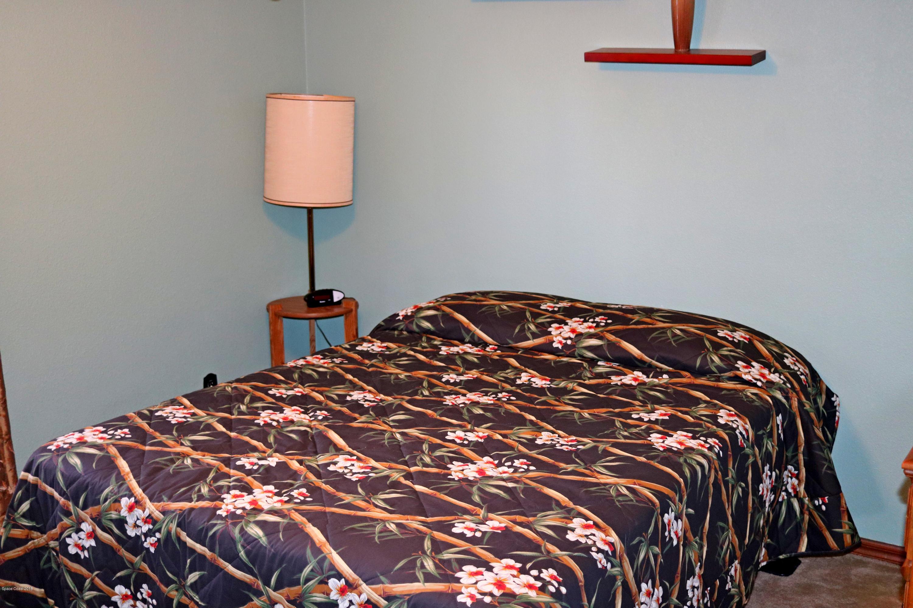 6154 Corning Road Cocoa, FL 32927 - Photo 10 of 16 a bedroom with a bed and a lamp