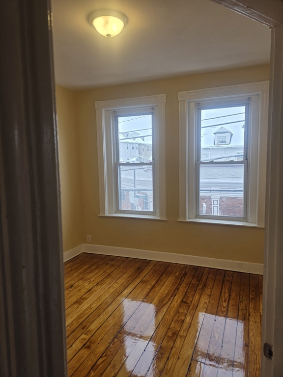 206 Harold Street, Unit 2 Boston, MA 02121 - Photo 4 of 7 a view of an empty room with wooden floor and a window