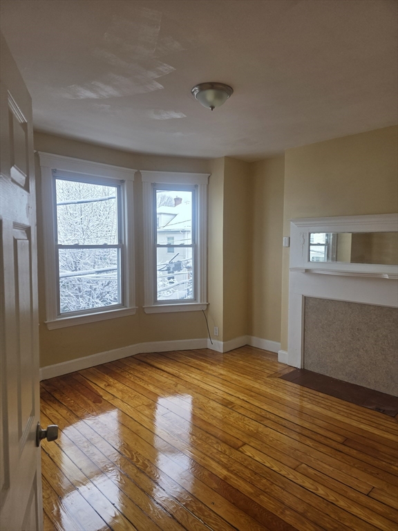206 Harold Street, Unit 2 Boston, MA 02121 - Photo 5 of 7 a view of an empty room with window and wooden floor