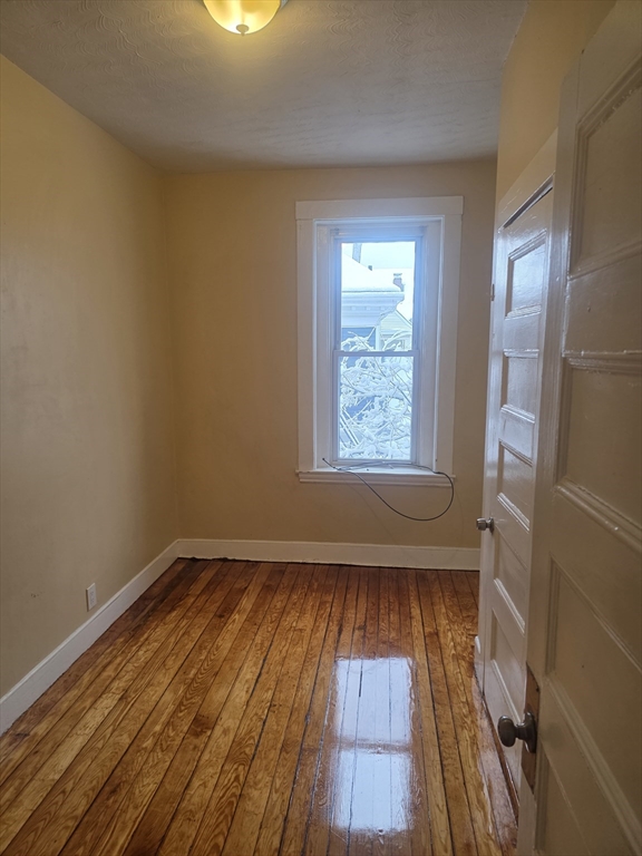206 Harold Street, Unit 2 Boston, MA 02121 - Photo 7 of 7 an empty room with wooden floor and windows
