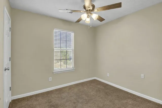 an empty room with windows and fan