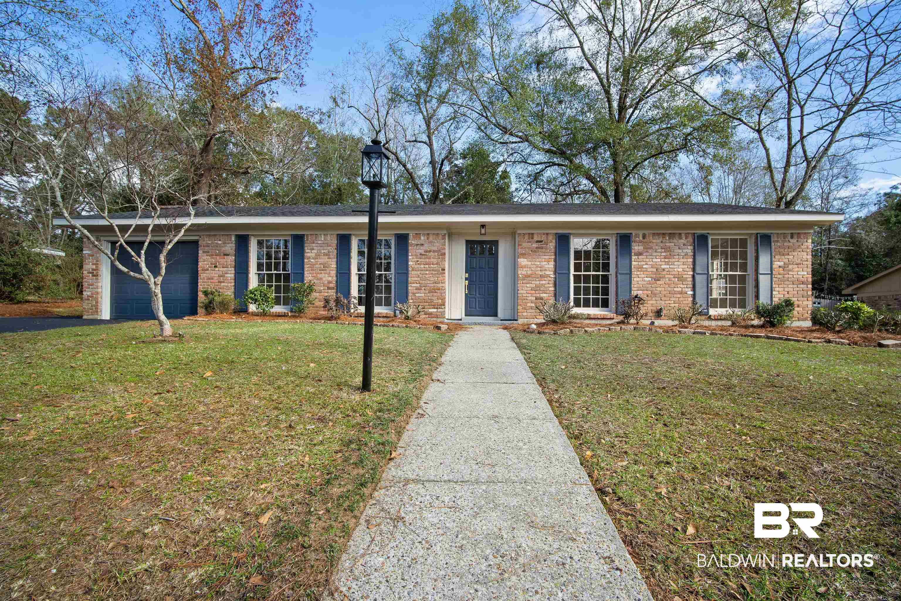 Ranch-style home featuring a front yard, brick siding, and a garage