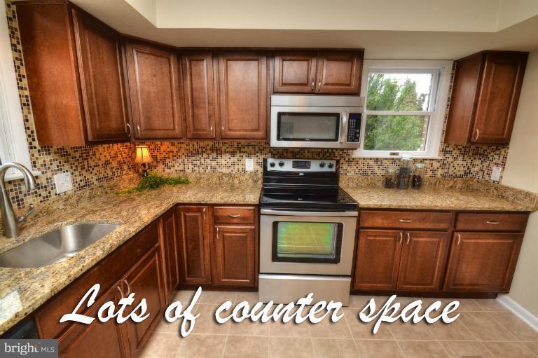 1302 Gransay Road Rosedale, MD 21237 - Photo 9 of 30 a kitchen with granite countertop wooden cabinets a sink a stove and a microwave