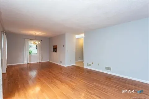 a view of empty room with window and wooden floor