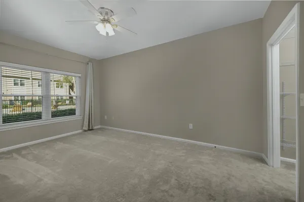 en empty room with windows and ceiling fan