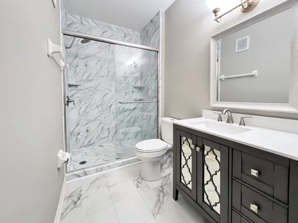 a bathroom with a granite countertop sink toilet a shower and a mirror