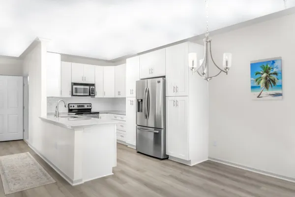 a kitchen with stainless steel appliances granite countertop a refrigerator a stove a microwave and white cabinets