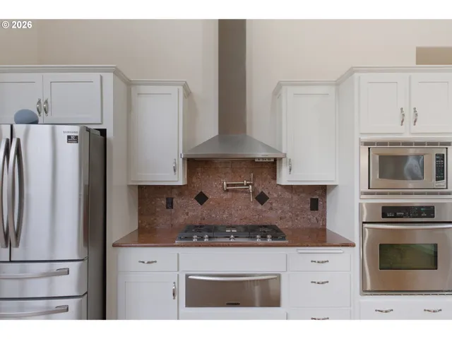 a kitchen with stainless steel appliances granite countertop a stove a refrigerator and a cabinets