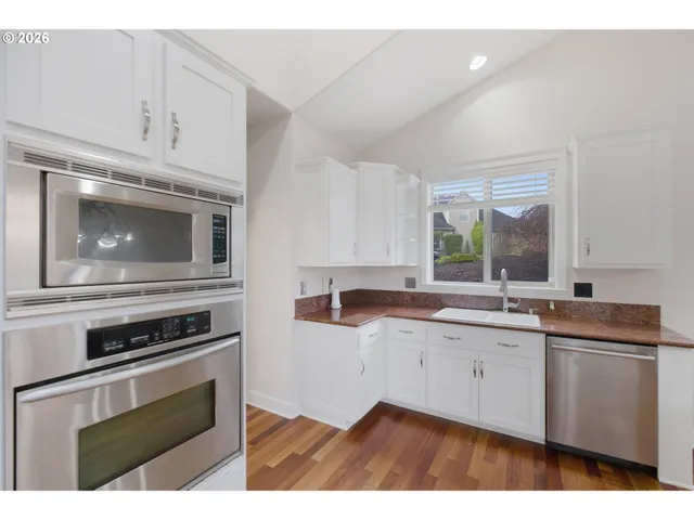a kitchen with granite countertop a sink cabinets stainless steel appliances and a window