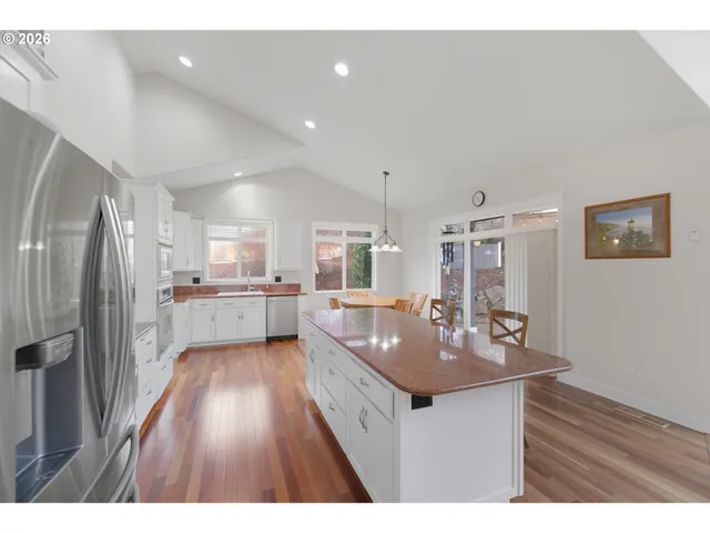 a kitchen with stainless steel appliances granite countertop a sink refrigerator and cabinets