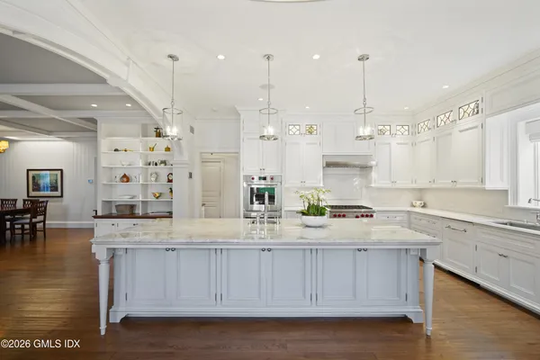 a large kitchen with kitchen island granite countertop a stove a sink a center island and cabinets