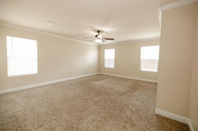 an empty room with windows and chandelier fan