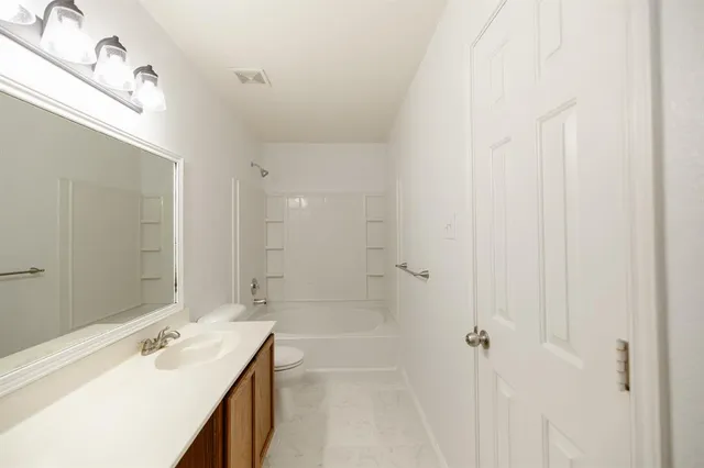a bathroom with a tub sink vanity granite and shower