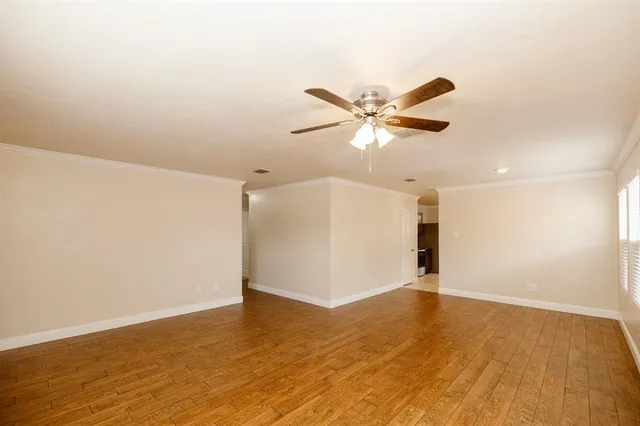 an empty room with wooden floor and ceiling fan