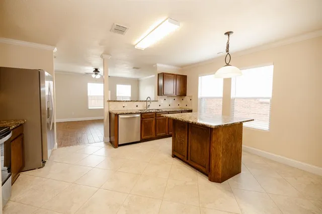 a kitchen with stainless steel appliances granite countertop a stove a sink a refrigerator and a counter top space