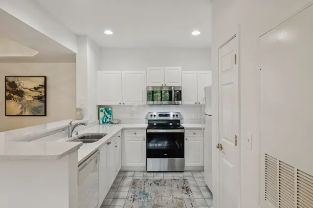 a kitchen with granite countertop a sink stainless steel appliances and white cabinets