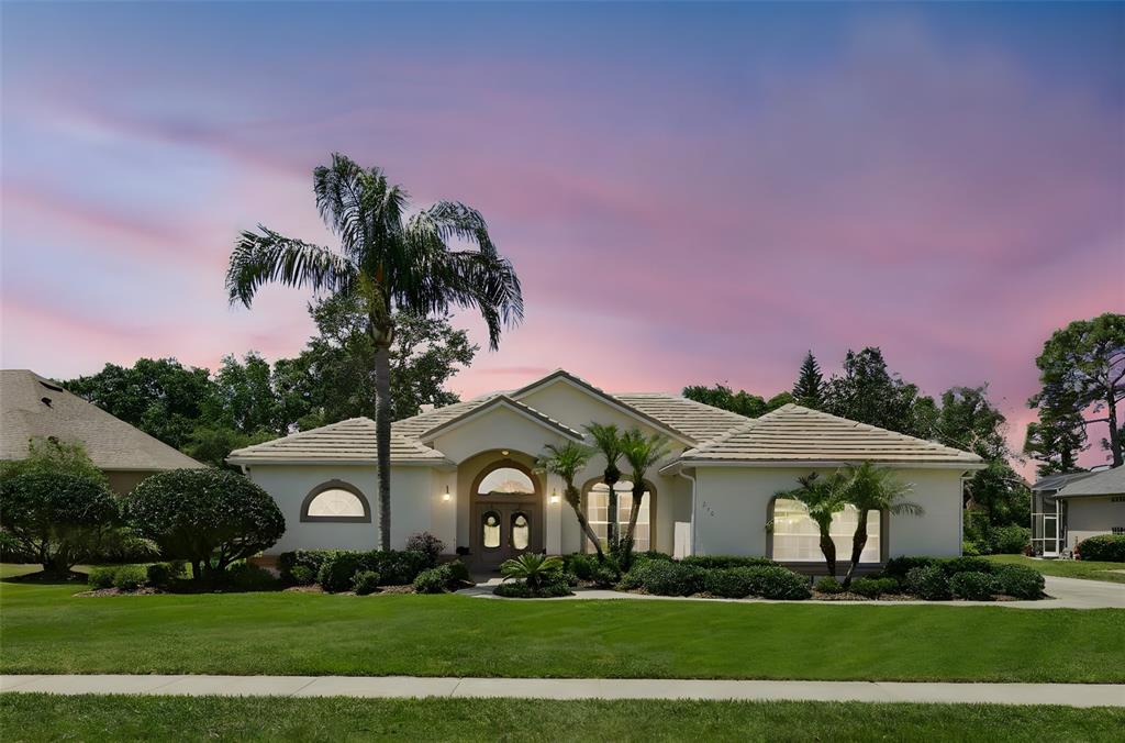 a front view of a house with a garden and trees