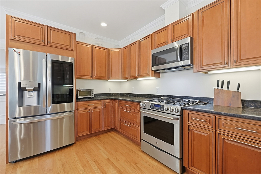 98-100 Lexington Street, Unit 100 Newton, MA 02466 - Photo 9 of 42 a kitchen with stainless steel appliances granite countertop a refrigerator stove top oven and sink