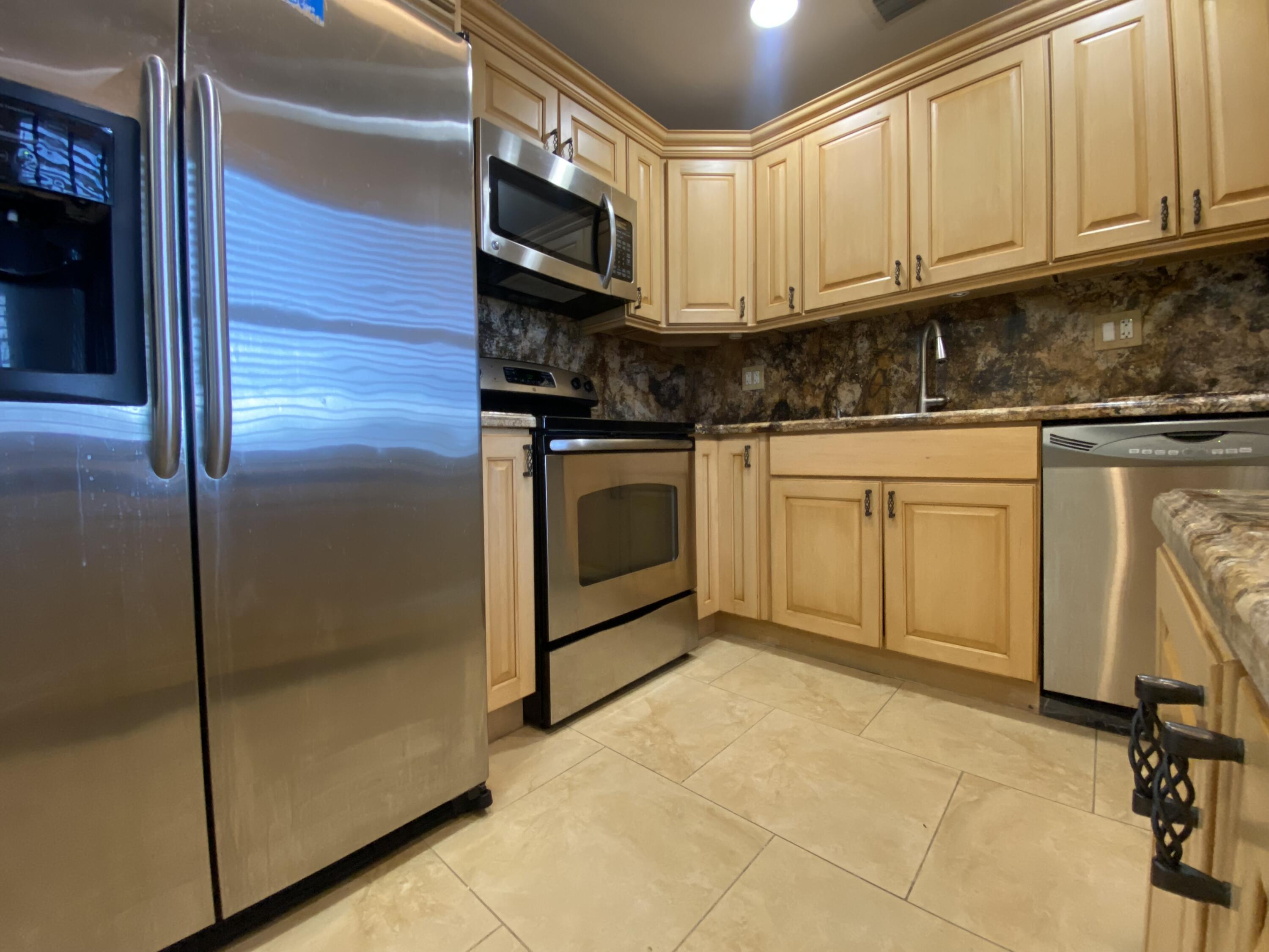 843 Flanders South Delray Beach, FL 33484 - Photo 2 of 29 a kitchen with stainless steel appliances granite countertop a refrigerator a stove and white cabinets