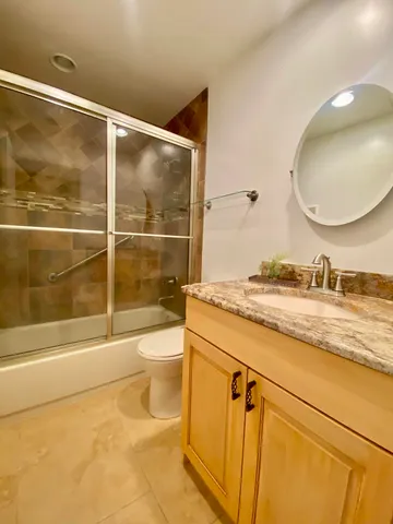 a bathroom with a granite countertop sink toilet and shower