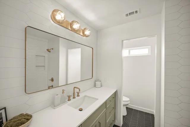 a bathroom with a sink a toilet and a mirror