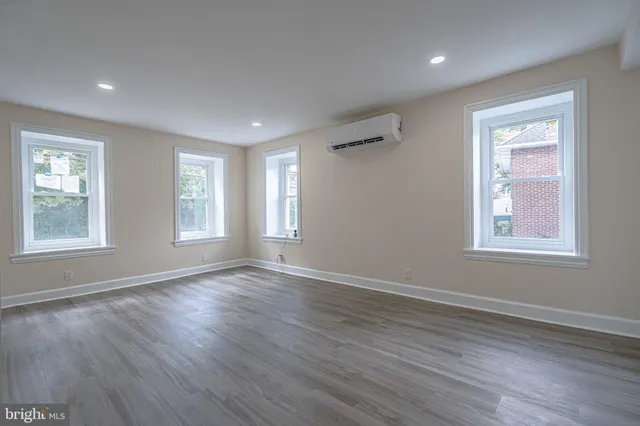 a view of an empty room with wooden floor and window
