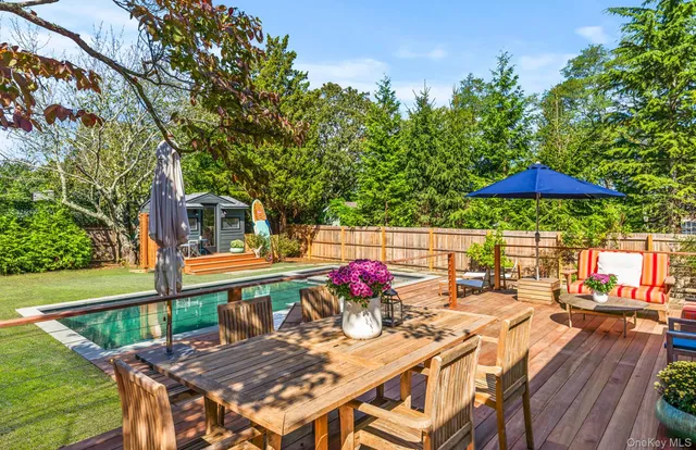 a view of a patio with table and chairs under an umbrella with wooden fence